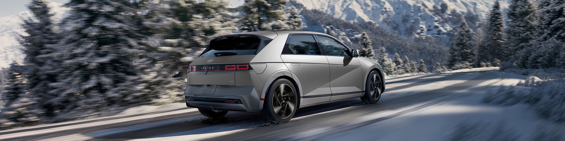 Side exterior view of Hyundai IONIQ 5 driving alonside snowy weather