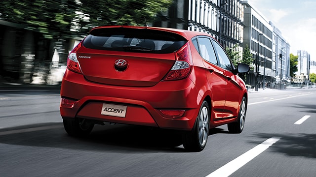 The exterior view behind the Hyundai Accent compact red hatchback car with five doors