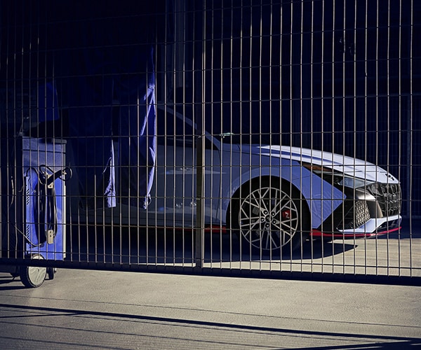 Chariot bleu à proximité d'une ELANTRA N 2022 bleue stationnée derrière une clôture 