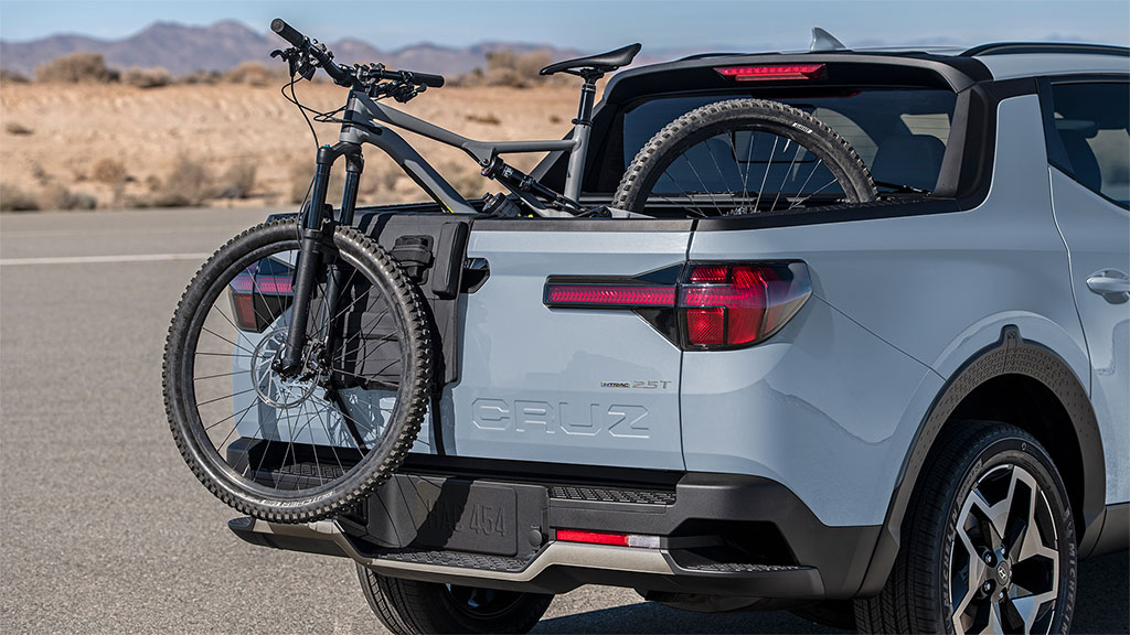 Bicycle resting out of the rear cargo bed in a blue 2022 Santa Cruz
