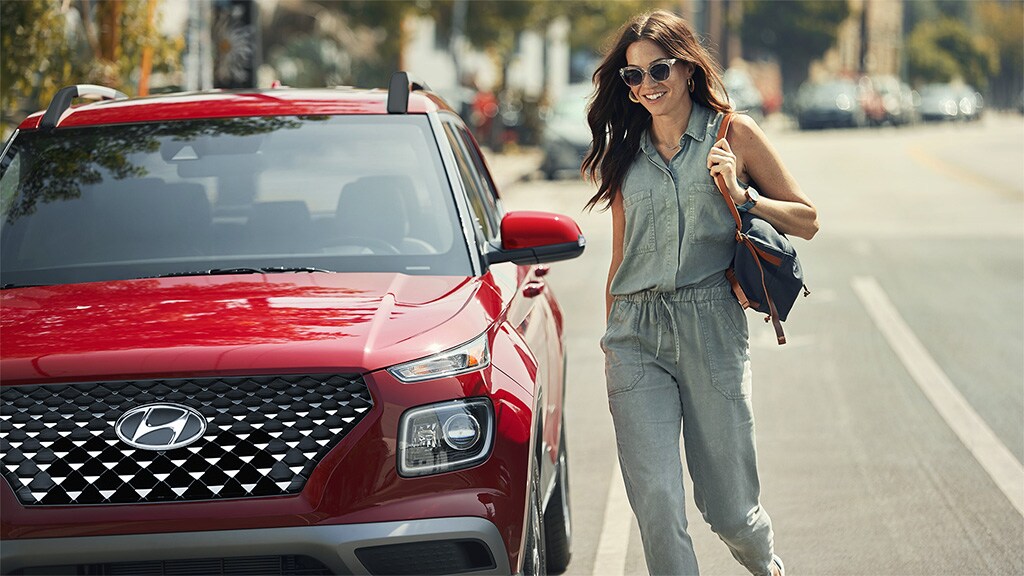 Modèle à côté d'un VENUE 2022 rouge stationné