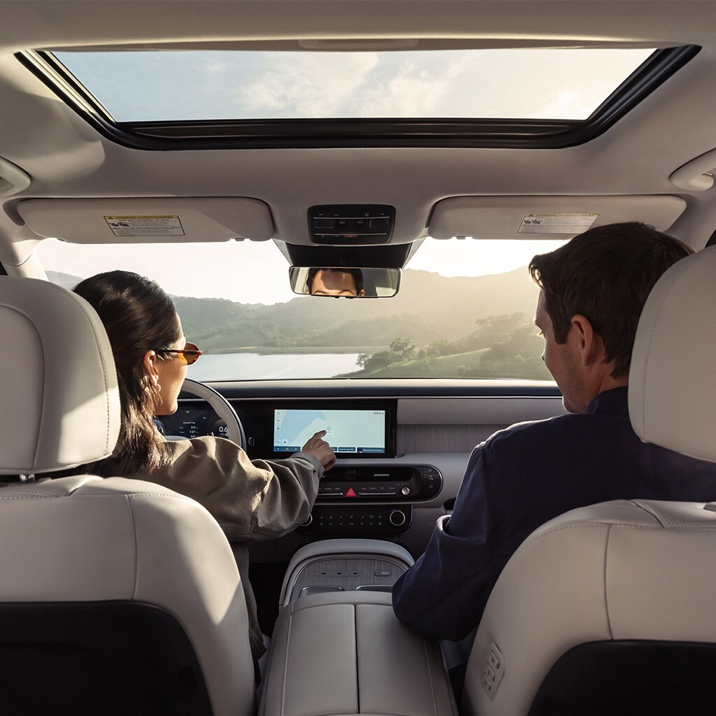 Une femme et un homme se détendent sous le toit ouvrant électrique de série d'un Palisade 2026